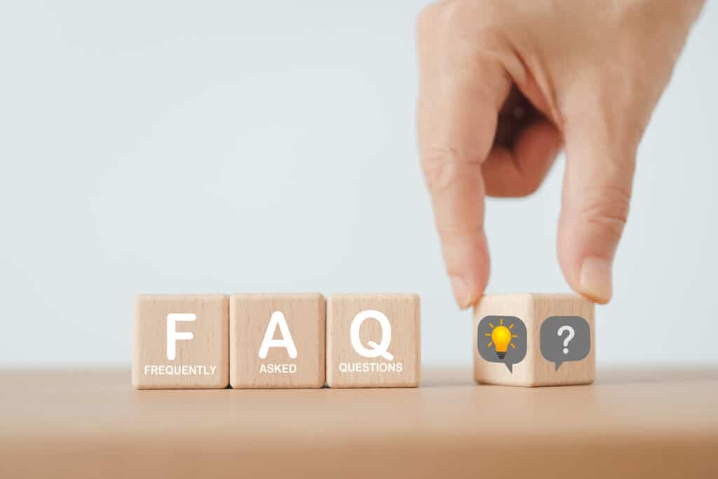 FAQ for Frequently asked questions concept, asked questions on any topic and answers. FAQ on wooden cube block with hand flipped question to lightbulb including copy space