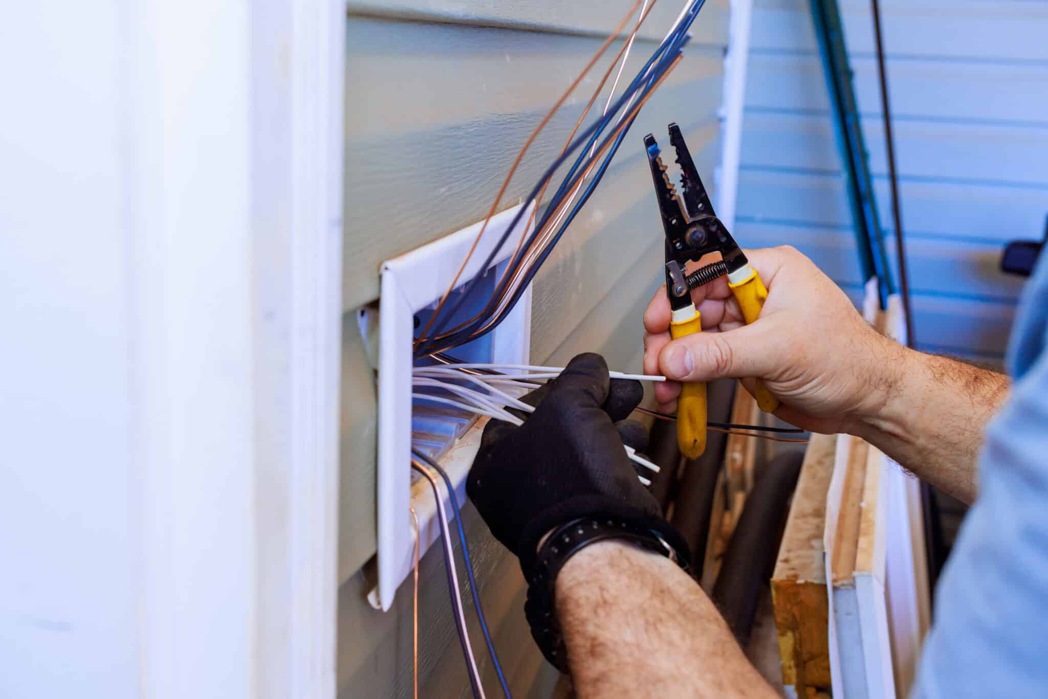 Contractor electrician uses tools to connect wires while during electrical work, Whole Home Rewiring.